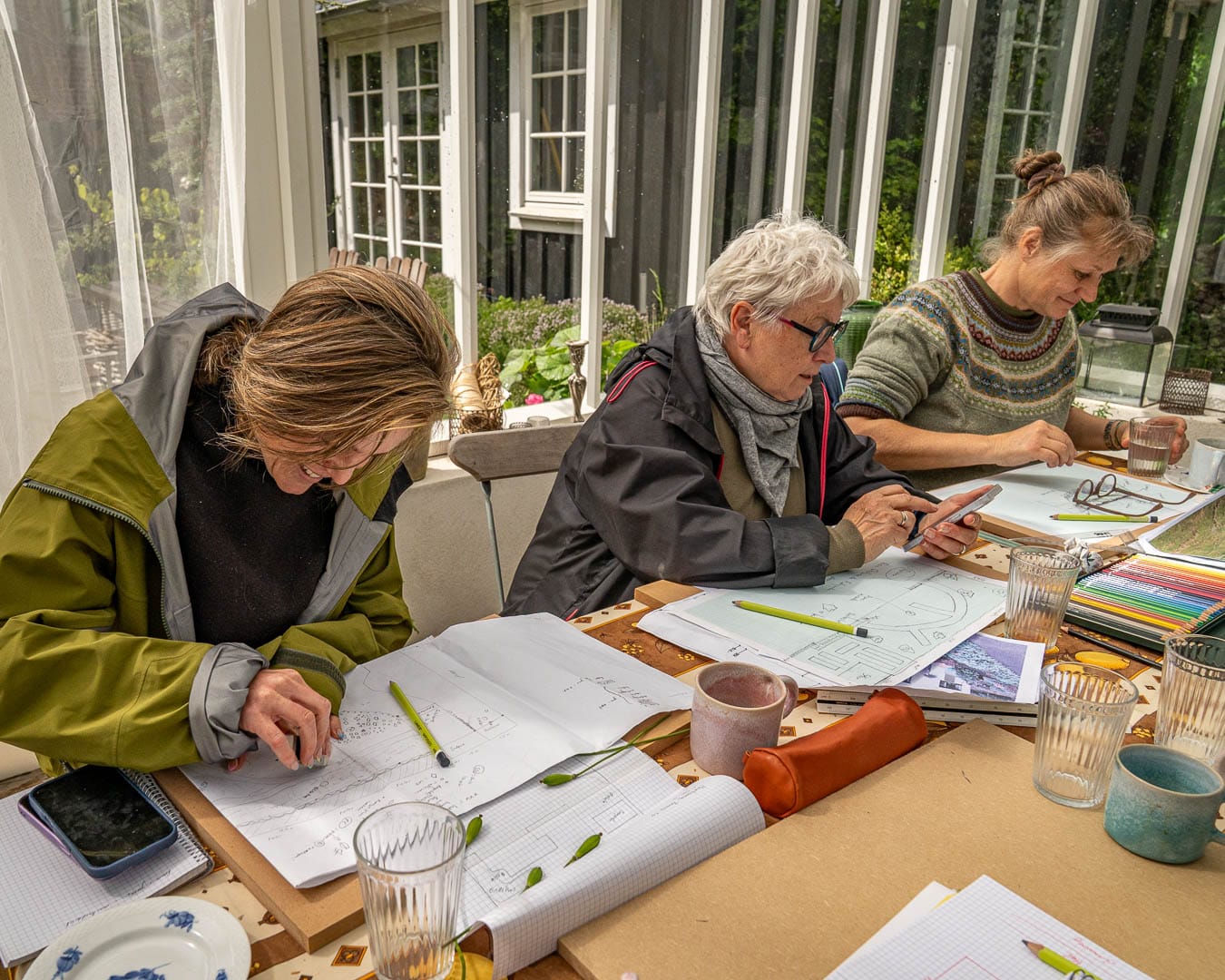 Kenn Römer-Bruhn underviser deltagere i orangeridesign ved tegnebord i Blomsterhaven