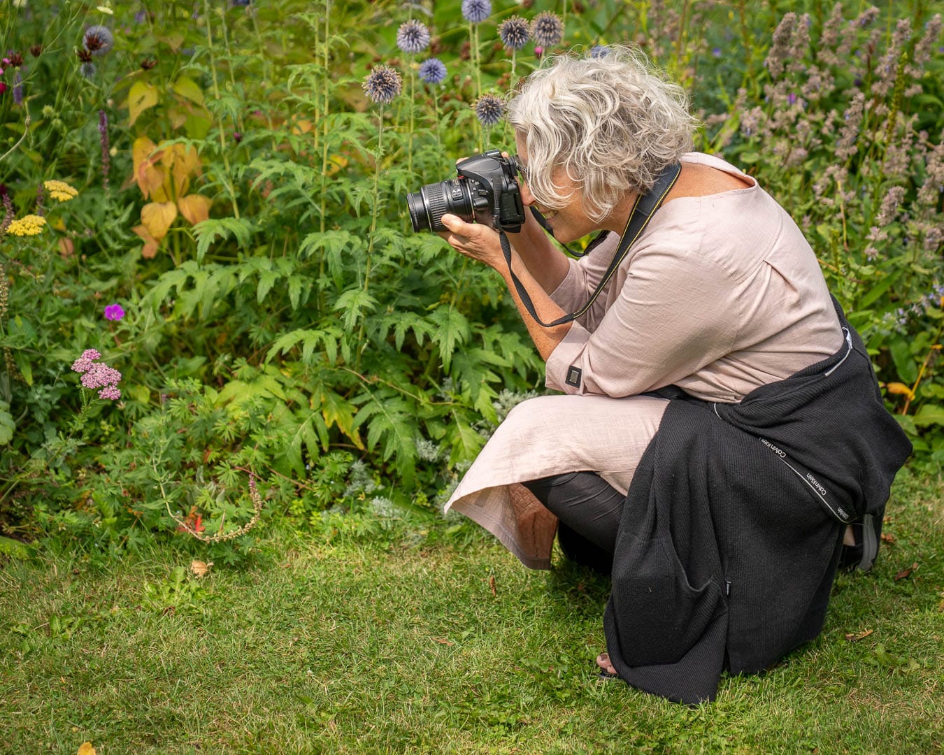 Deltager fotograferer blomster i et staudebed i Blomsterhaven