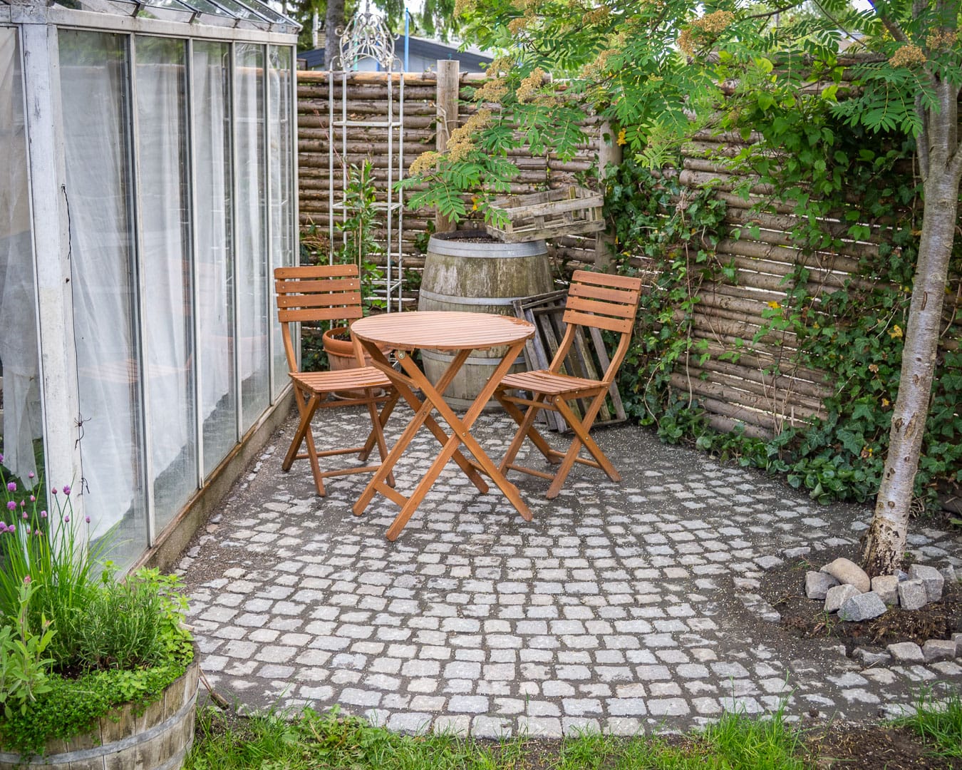 Hjemmebygget drivhus Hjemmebygget drivhus og terrasse med chaussesten